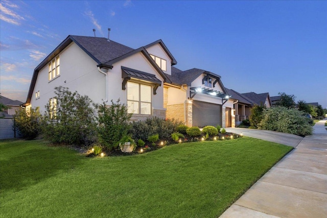 view of front of property featuring stone siding, concrete driveway, a garage, a front yard, and stucco siding
