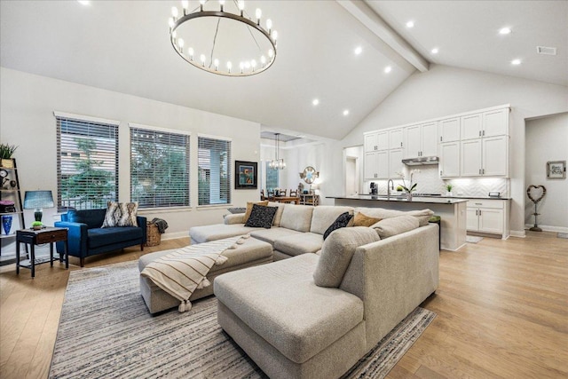 living area featuring light wood-type flooring, beam ceiling, baseboards, high vaulted ceiling, and a notable chandelier