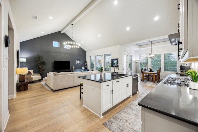 kitchen with an inviting chandelier, dark countertops, light wood-style floors, high vaulted ceiling, and white cabinetry