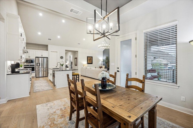 dining room with light wood-type flooring, visible vents, baseboards, and an inviting chandelier