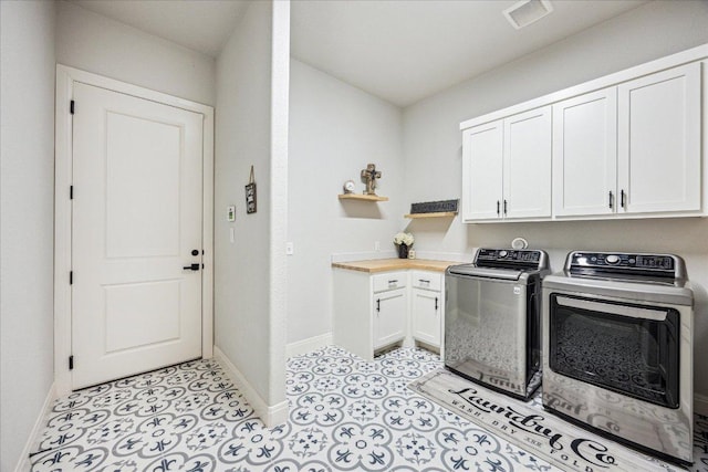 washroom featuring washing machine and clothes dryer, baseboards, visible vents, and cabinet space