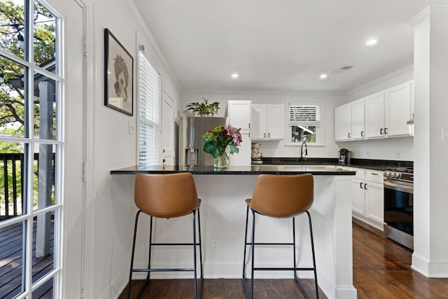 2844 Shoal Crest Ave, Austin, TX 78705 - kitchen with dark countertops, white cabinetry, a breakfast bar area, and stainless steel appliances