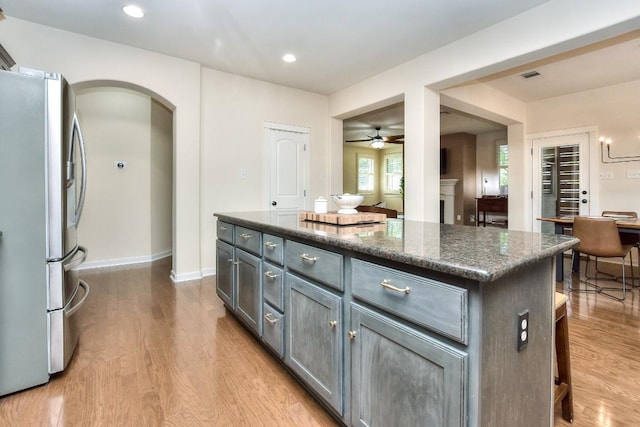 110 Chestnut Ct, Georgetown, TX 78633 - kitchen featuring freestanding refrigerator, arched walkways, wood finished floors, ceiling fan, and a center island