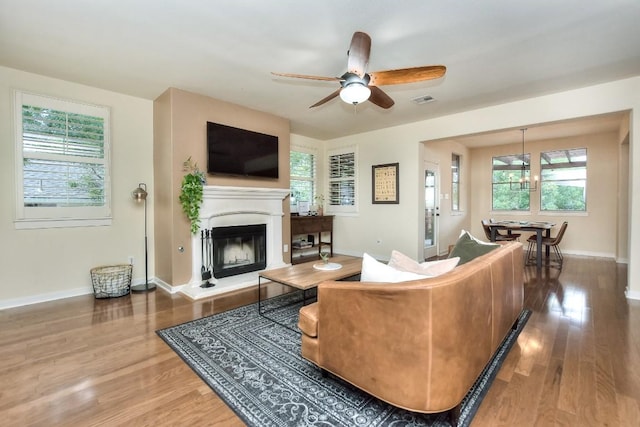 110 Chestnut Ct, Georgetown, TX 78633 - living room featuring a glass covered fireplace, wood finished floors, a ceiling fan, baseboards, and a chandelier