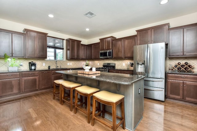 110 Chestnut Ct, Georgetown, TX 78633 - kitchen with appliances with stainless steel finishes, a kitchen breakfast bar, a kitchen island, wood finished floors, and dark brown cabinets