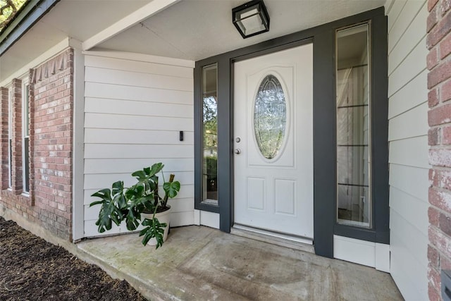 property entrance with brick siding and a porch
