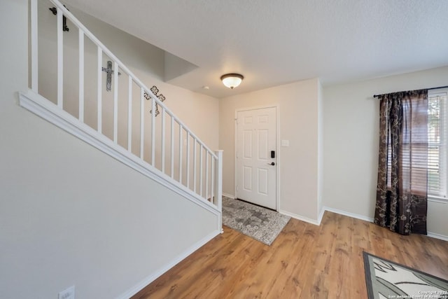 foyer entrance featuring stairs, baseboards, and light wood-style floors