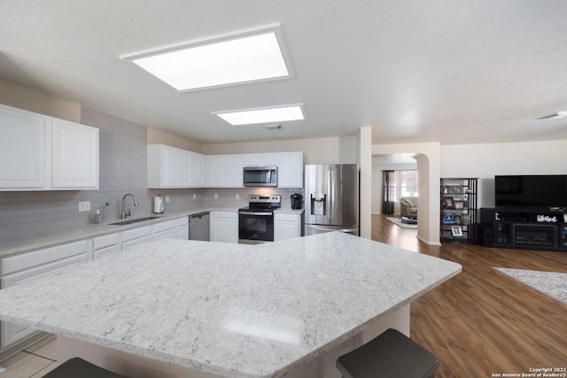 kitchen featuring backsplash, white cabinets, stainless steel appliances, and a sink