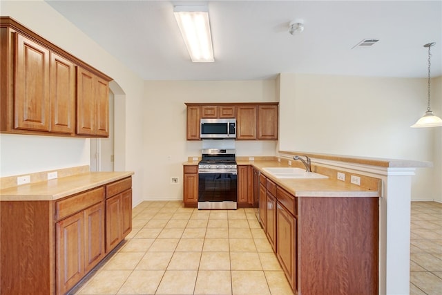 10916 Furrow Hill Dr, Austin, TX 78754 - kitchen with stainless steel appliances, light tile patterned flooring, light countertops, a peninsula, and brown cabinetry