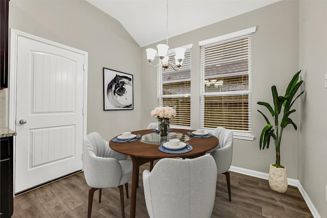 dining room featuring wood finished floors, a chandelier, vaulted ceiling, and baseboards