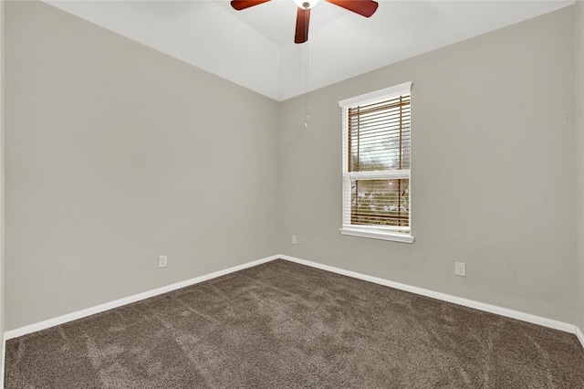 empty room featuring dark colored carpet, a ceiling fan, and baseboards