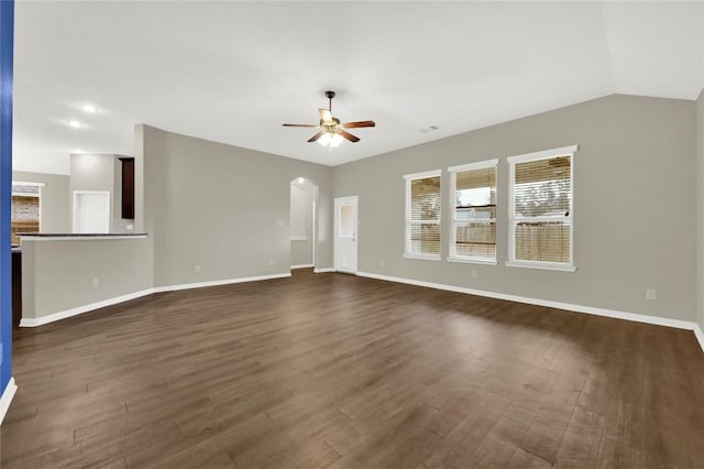 unfurnished living room featuring a ceiling fan, dark wood-style floors, baseboards, arched walkways, and lofted ceiling