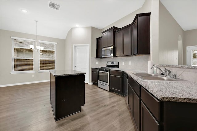 kitchen with stainless steel appliances, a sink, lofted ceiling, backsplash, and light wood finished floors