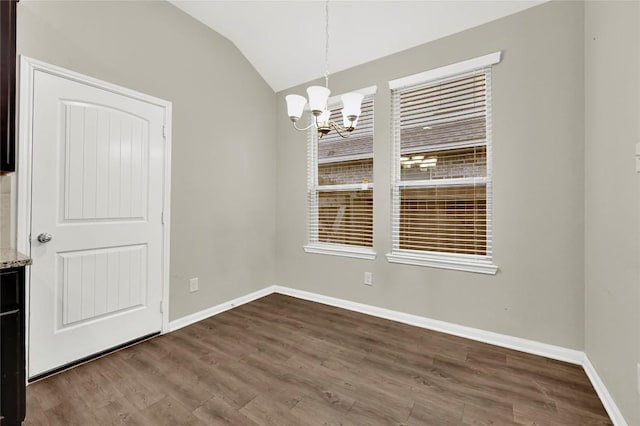 unfurnished dining area with a chandelier, dark wood-style flooring, baseboards, and lofted ceiling