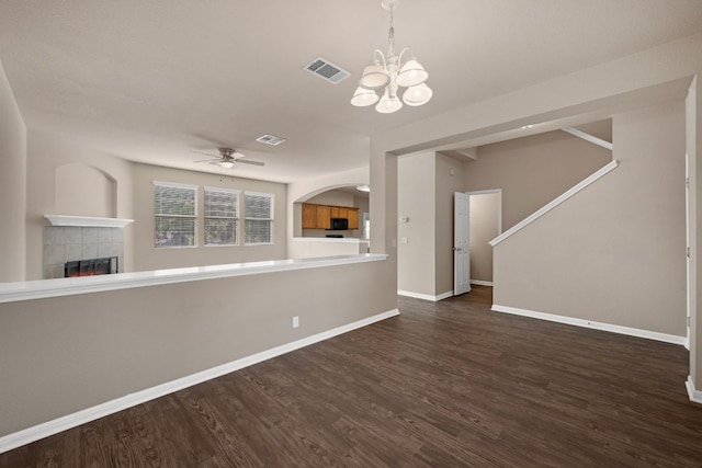 unfurnished living room featuring ceiling fan with notable chandelier, a tiled fireplace, wood finished floors, and visible vents