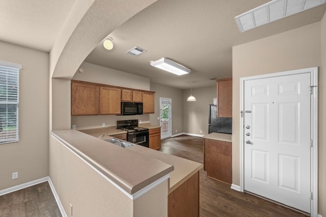 kitchen featuring dark wood-style floors, a sink, brown cabinetry, black appliances, and visible vents