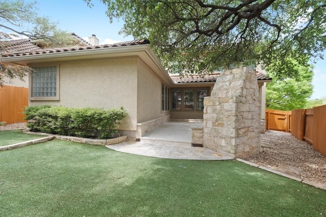 rear view of house with a tiled roof, fence private yard, and stucco siding