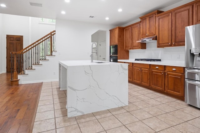 kitchen featuring recessed lighting, under cabinet range hood, visible vents, a sink, and black appliances