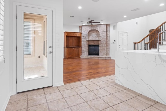 unfurnished living room with recessed lighting, stairs, ceiling fan, a stone fireplace, and light tile patterned floors