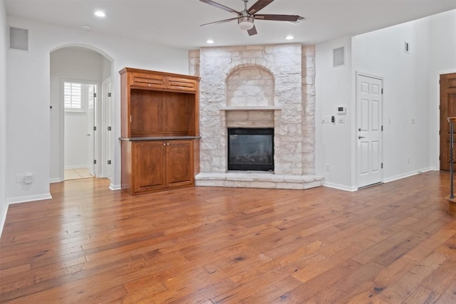unfurnished living room with arched walkways, recessed lighting, ceiling fan, hardwood / wood-style flooring, and a fireplace