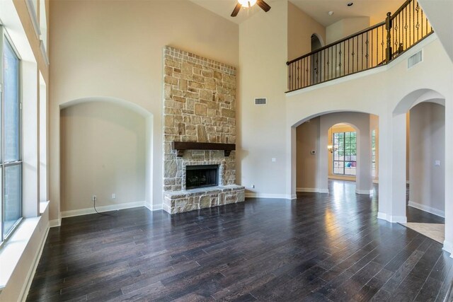 308 Angus Dr, Cedar Park, TX 78613 - unfurnished living room with a ceiling fan, a high ceiling, wood finished floors, a stone fireplace, and arched walkways