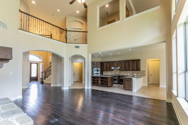 308 Angus Dr, Cedar Park, TX 78613 - unfurnished living room with arched walkways, a ceiling fan, stairway, light wood-style floors, and a high ceiling