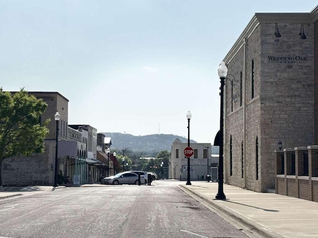 view of street featuring street lighting, sidewalks, traffic signs, and curbs