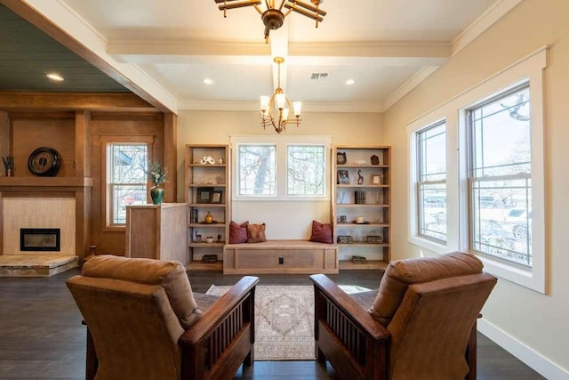 living area with a large fireplace, dark wood finished floors, a notable chandelier, beam ceiling, and visible vents