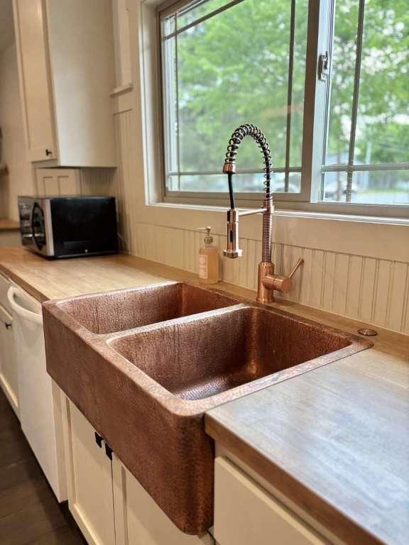 kitchen with white cabinets, light countertops, dishwasher, and a sink