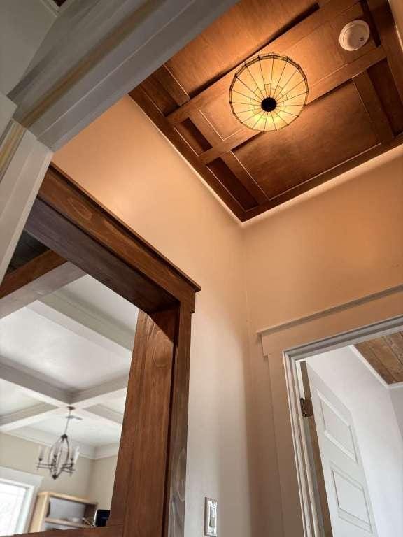 interior details featuring coffered ceiling, a notable chandelier, and beamed ceiling