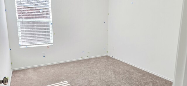 carpeted spare room featuring baseboards