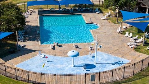 pool with a water play area, fence, and a patio