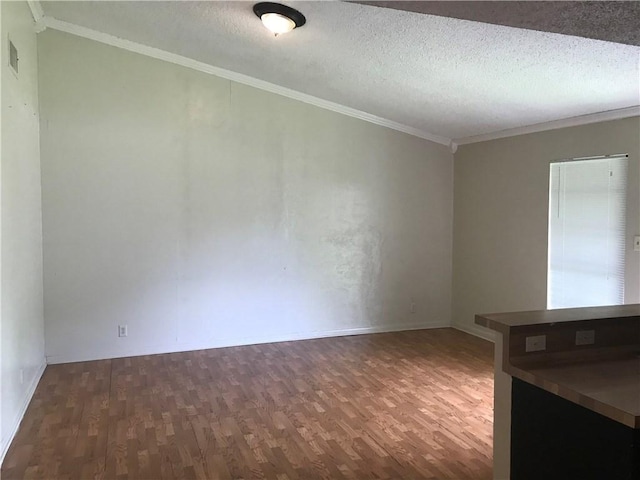 interior space featuring wood finished floors, a textured ceiling, crown molding, and baseboards
