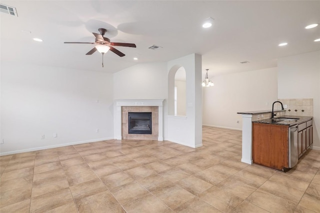 1317 Rimstone Dr, Cedar Park, TX 78613 - unfurnished living room with recessed lighting, a ceiling fan, a tile fireplace, arched walkways, and a chandelier