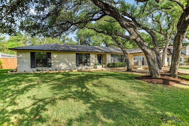 ranch-style home with brick siding, a front yard, and fence
