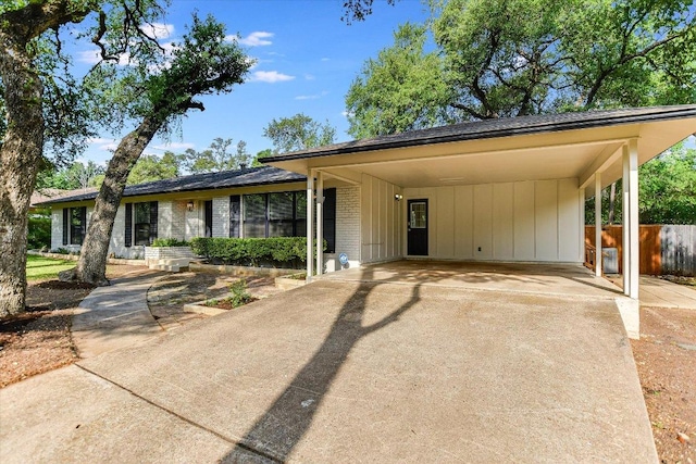 view of front facade featuring board and batten siding, fence, brick siding, and concrete driveway