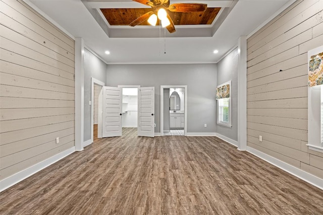 unfurnished living room featuring wood walls, a ceiling fan, wood finished floors, and a raised ceiling