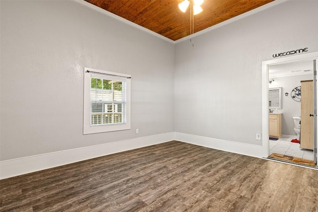 spare room featuring baseboards, wood finished floors, crown molding, and wooden ceiling