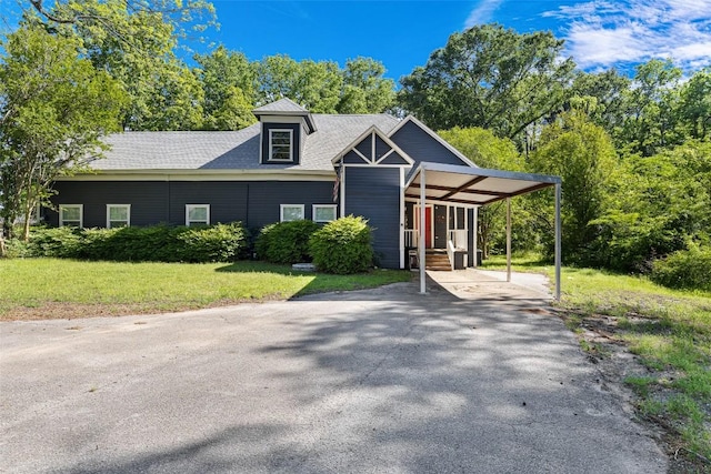 view of front of house featuring driveway, a shingled roof, a front lawn, and an attached carport