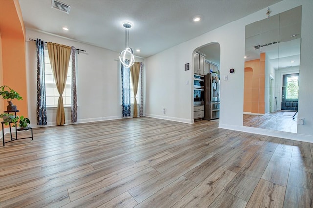 1117 Arbor Acres Loop, Leander, TX 78641 - unfurnished living room with arched walkways, light wood-type flooring, baseboards, and recessed lighting