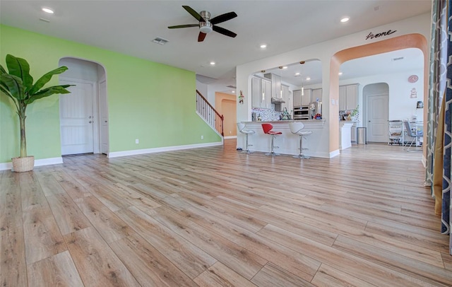 1117 Arbor Acres Loop, Leander, TX 78641 - unfurnished living room featuring ceiling fan, arched walkways, light wood-style floors, stairway, and recessed lighting
