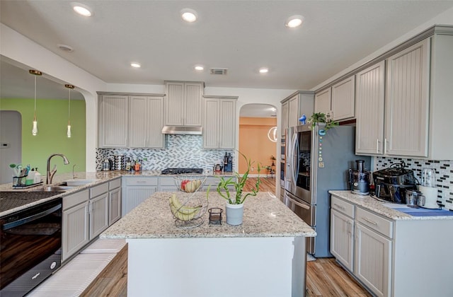 1117 Arbor Acres Loop, Leander, TX 78641 - kitchen with arched walkways, black dishwasher, freestanding refrigerator, under cabinet range hood, and a center island