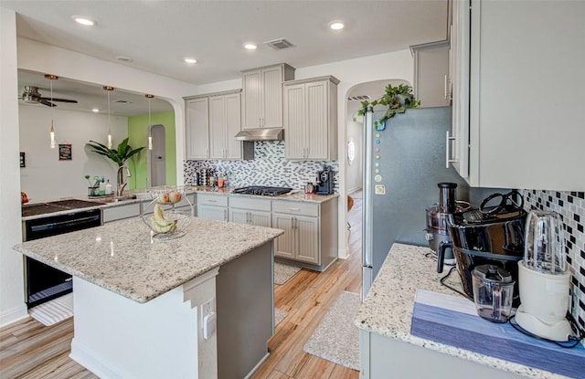 1117 Arbor Acres Loop, Leander, TX 78641 - kitchen with arched walkways, under cabinet range hood, light wood-type flooring, decorative backsplash, and recessed lighting