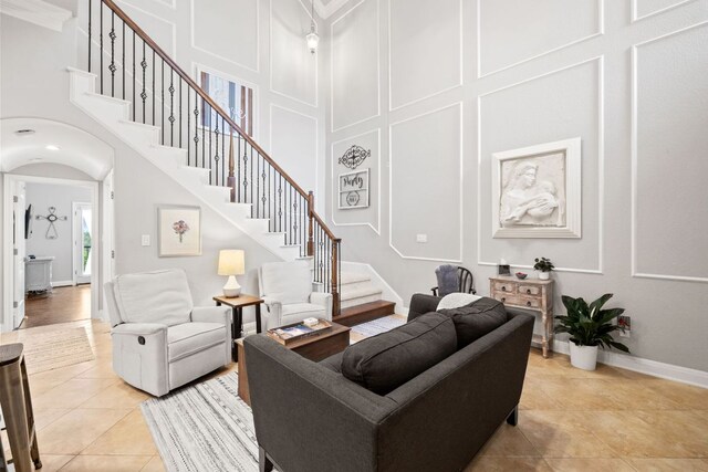 218 Sunrise Ridge Loop, Lakeway, TX 78738 - living room featuring a towering ceiling, stairway, light tile patterned floors, a decorative wall, and arched walkways
