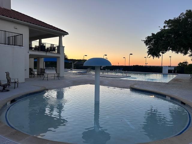 218 Sunrise Ridge Loop, Lakeway, TX 78738 - pool at dusk with a community pool and a patio area