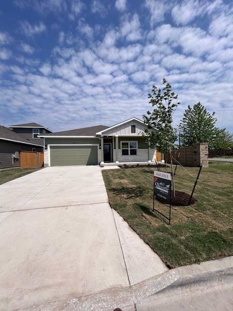 view of front of home featuring driveway, fence, a front yard, and a garage