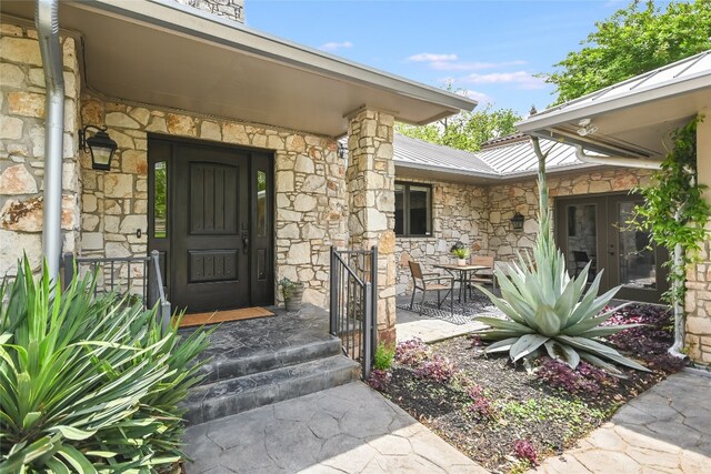 2305 Manana St, Austin, TX 78730 - doorway to property featuring stone siding, metal roof, and outdoor dining area