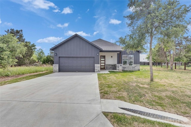 modern home featuring concrete driveway, a front lawn, stone siding, and a garage