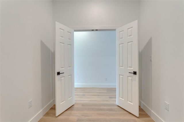 corridor featuring baseboards and light wood-style floors