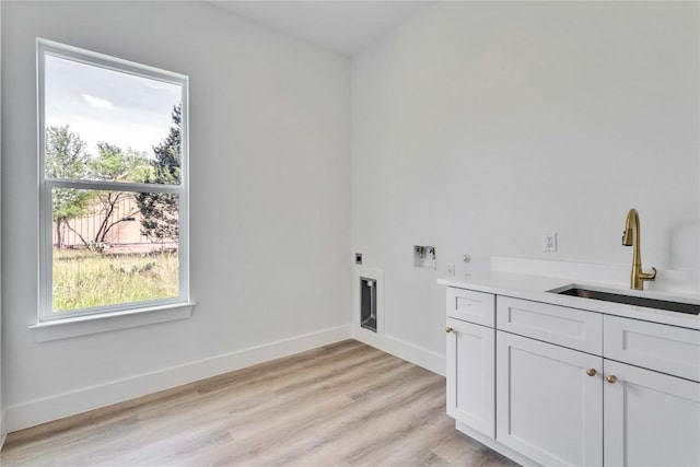 laundry area featuring a sink, hookup for an electric dryer, cabinet space, light wood-style flooring, and baseboards